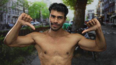 Çıplak göğsü olan, güneşli şehir caddesinde güvenle baş parmak işareti yapan, onaylanmayan, çıplak bir adam..