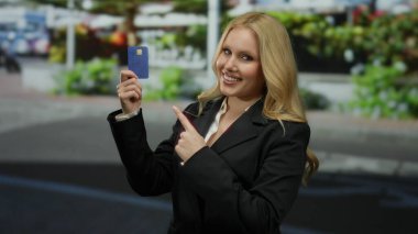 Mavi kredi kartı tutan takım elbiseli genç bir kadın. Geçmişi bulanık. Finansal hizmeti veya kişisel bankacılık güvenini gözler önüne seriyor..