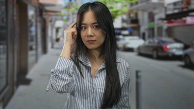 Şehirli sokak ortamını işaret eden kadın, hareketli bir şehirde çevresini çevreleyen hareketli doğa koşullarıyla meşgul olurken, kendi ifadesiyle odaklanıyor ve kararlılığını ifade ediyor..