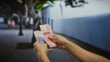 Kentsel caddede İsviçre banknotları elinde tutan adam, açık şehir ortamında para ve yatırımı vurguluyor.