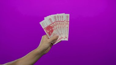 İzlanda krona banknotları, canlı bir mor duvar arka planına karşı, para ve finans kavramlarını vurgulayarak,.