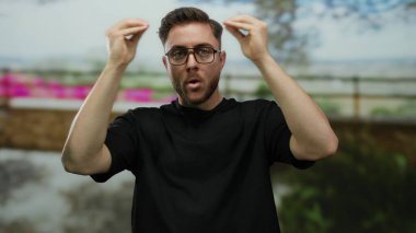 Sakallı genç, beyaz bir adam, şehir dışındaki bir sokak ortamında, şehir duygularını ve ifadesini aktararak stres yapıyor..