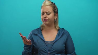 Stüdyoda mavi ceketli sarışın kadın parmaklarını odaklanmış ifadeyle ve çatık kaşlı kaşlarıyla sayıyor; belirsizlik..