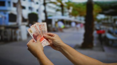 Norveç kronu banknotları elinde tutan adam hareketli bir şehir caddesinde iş ve yatırım kavramlarını ön plana çıkarıyor..