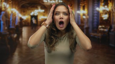 Kadın süslemelerle ve parıldayan ışıklarla çevrili bir müzede canlı bir deneyim sergileyerek sürpriz ve neşe ifade ediyor..