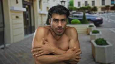 İnsan çıplak kaslı kollarını gösterir ve onları çenesinin altında sıkıca çaprazlar boş bir şehir caddesinde soğukta ürperirken; soğuk huzursuzluk.