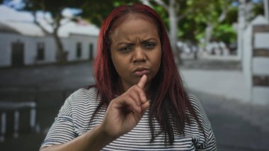 Genç Afrikalı Amerikalı kadın, şehir sokaklarında reddedilme jestinde uzamış parmağını işaret ediyor..
