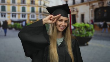 Mezuniyet üniformalı, açık hava seremonisi sırasında sokaklarda gülümseyen akademik başarı ve başarıyı temsil eden beyaz bir kadın..