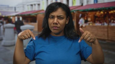 Kaşlarını çatarken mavi gömleğini aşağı doğru gösteren bir kadın. Hayal kırıklığı..