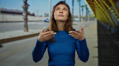 Şehir sokaklarında meditasyon yapan bir kadın sakin, gözleri kapalı, mavi süveter giyen sakin ve düşünceli.