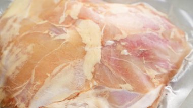 Vakumlanmış çiğ tavuk göğsü, tazeliğini ve dokusunu vurgulayarak yakın plan çekimde sergilenir.