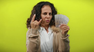 Orta yaşlı bir kadın taştan bir jest yapıyor ve sarı bir arka plana karşı Singapur doları tutuyor..