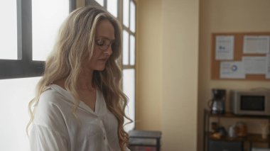 İş yerinde uzun sarı saçlı, ofis ortamını yansıtan uzun saçlı bir kadın düşünceli bir ruh hali ya da profesyonel bir ortam öneriyor..