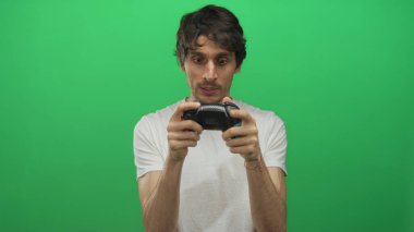 Stüdyoda elinde siyah kablosuz oyun kumandası olan genç bir adam odaklanmış bakıyor; yoğun konsantrasyon becerisi ustalığı.