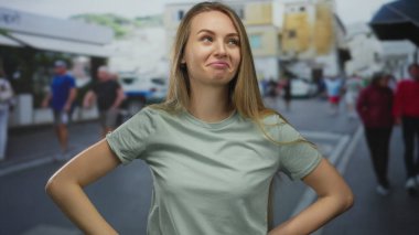 Hareketli bir şehir caddesinde rahat bir şekilde dikilen kadın, günlük giysiler içinde, hayat dolu şehir zemininin ortasında kendine güvenin ve sevincin ifadesini canlandırıyor..