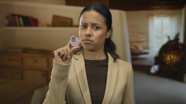 ABD rozetini içinde tutan kadın sıcak bir oda ortamında düşünceli bir ifadeyle, kimliğini, uyruğunu ve kişisel yansımasını ön plana çıkarıyor..