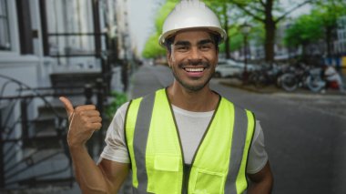 Kasketli ve yansıtıcı yelekli adam, bisiklet dolu şehir caddesinde başparmak kaldırıyor; iyimserlik hırsı olan başarı.