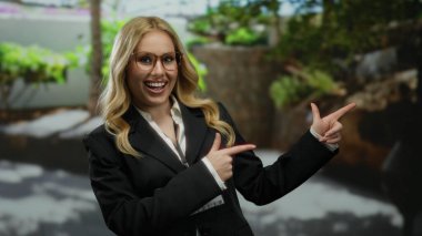 Parkta gülümseyen bir kadın güvenli bir şekilde arka planda yeşil ağaçlarla işaret ediyor.