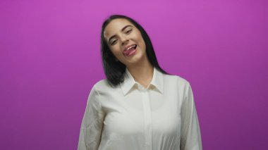 Neşeli pembe arka planda, neşeli ve eğlenceli bir kişiliği olan, gençlik ve pozitiflik temalı içerik için canlı bir ortamda neşeli bir şekilde dilini dışarı çıkaran bir kadın.