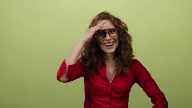 Alnında kırmızı tişörtle, sarı arka planda gülümseyen bir kadın arkadaşça bir ifadeyle neşe ve mutluluk saçıyor.