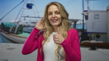 Kadın, açık deniz kenarında genç bir sarışınla limanda konuşurken kulak misafiri oluyor. Tuhaf bir gülümseme sergiliyor..