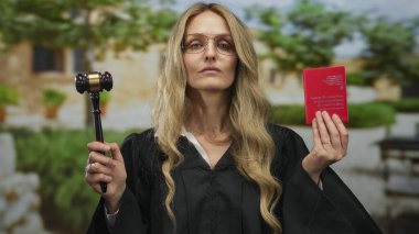 Kadın, İsviçre 'de elinde pasaport ve tokmak, otoriteyi yansıtan sarı saç ve doğal bir arka fona karşı kimlik doğrulama yargıcı..