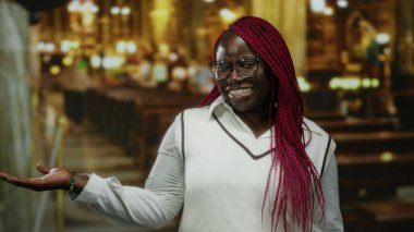 Geniş bir el ile gülümseyen bir kadın loş bir kilisede ahşap sıralarla, olumlu ve hoş bir atmosfer sergiliyor..