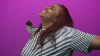 Kollarını genişçe açan bir kadın ışıldayan bir gülümseme ile, yüzü yukarı döndü ve uzun kızıl saçlı mor bir stüdyo; sevinç;.