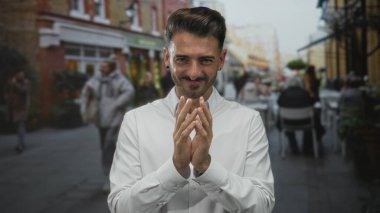 Adam açık hava tabloları ile tuğla mağaza önünde sokakta el çırpıyor parlak kentsel gün; beklenti.