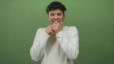 Yumuşak ışıklandırma altında yeşil stüdyoda tırnaklarını gergin yüzüyle yiyen genç İspanyol adam..