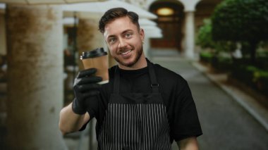 Sakallı, önlüklü ve eldivenli genç bir adam şehir caddesinde kahve ikram ediyor. Açık hava kafe havasını canlı bir şehir ortamında somutlaştırıyor..
