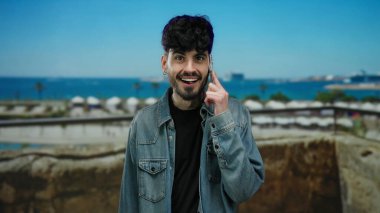 Manzaralı deniz kıyısında, arka planda okyanus manzaralı akıllı telefondan konuşan bir adam günlük şehir yaşam tarzını sergiliyor..