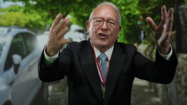 Takım elbiseli, madalyalı kıdemli bir adam sokaklarda arabalarla ve ağaçlarla dolu neşeli bir şekilde eğleniyor. Başarı ve kutlama hissi yayıyor..