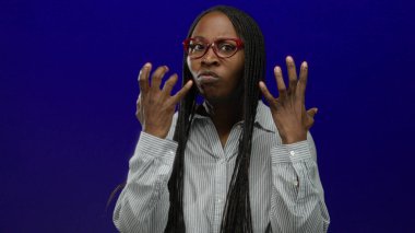 Gözlüklü ve örgülü bir kadın öfkesini mavi duvara yumruk atarak ifade ediyor. Duygularını ve gücünü sergiliyor..