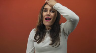 Stüdyo ortamında canlı kırmızı arkaplan karşısında şaşkınlığını dile getiren kadın duygu ve yoğunluğu yakalıyor..
