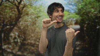 Gri gömlekli adam gündüz vakti güneşli yeşil orman yolunda göğsünü işaret ediyor. Kendine güven..
