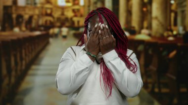 Kırmızı örgülü, gözlüklü bir kadın kilisenin içinde yüz yüze, manevi bir ortamda duygularını ifade ediyor..