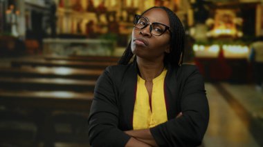 Kıvırcık saçlı bir kadın kilise ortamında hayal kırıklığını ifade ediyor. Güzel bir duygu anı yaşıyor..