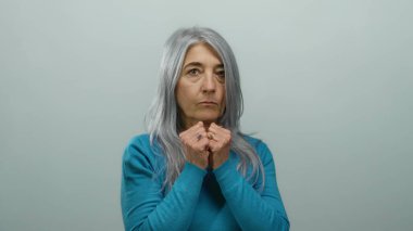 Beyaz arka planda mavi gömlekli son sınıf öğrencisi kadın. Yumruk duruşunu ve gücünü gösteriyor. Odaklanmış ifadesi sade bir ortama karşı.