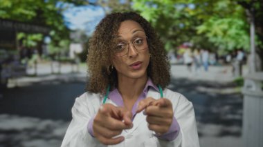 Stetoskop ve gözlüklü kadın doktor, kamerayı caddeye doğrultuyor..