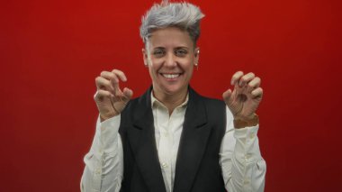 Kısa, gümüş saçlı, gülümseyen elleri olan bir kadın pençe jest stüdyosu gösteriyor; neşe dolu bir eğlence..