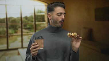 Adam waffle tadıyor ve kanepenin yanında kahve fincanı tutuyor..