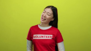 Kırmızı gönüllü gömlekli kadın neşeli sarı bir arka planda neşeli ve toplum temalı ifadeleri canlandırarak neşeli bir şekilde gülümsüyor..