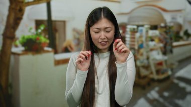 Gün boyunca hareketli bir şehir caddesinde duygularını ifade eden uzun saçlı bir kadın. Arka planda pazarlar ve dükkanlar var..