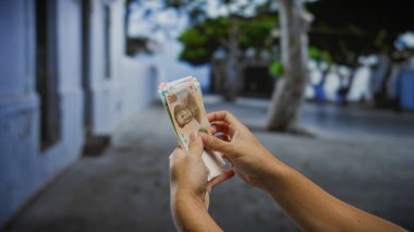 Paraya ve bulanık bir geçmişe odaklanmış, şehir merkezindeki finansal ya da ekonomik temayı tasvir eden kentsel caddede Çin Yuanı banknotları tutan adam..