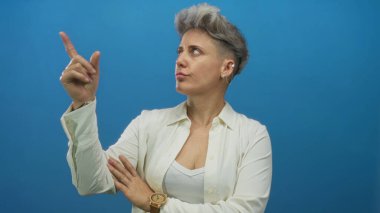 Beyaz gömlek giyen, stüdyoda parmaklarını sağa sola gösteren kadın, merak uyandıran içgörü yansıması.