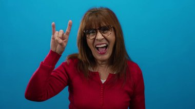 Mavi arka planda kırmızı kazaklı kadın gülümsüyor ve elinde enerjik bir şekilde rock 'n' roll hareketi yapıyor neşeli ve dışa dönük bir ruh haline bürünüyor..