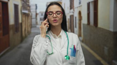 Üniformalı ve steteskoplu bir doktor, sessiz bir caddede dikiliyor, profesyonelliği ve açık hava koşullarını aktarıyor..