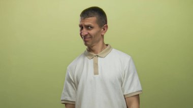 Beyaz gömlekli, kısa saçlı ve tarafsız ifadeli sıradan sarı arka planda duran bir adam şüphecilik ya da belirsizliği akla getiriyor.