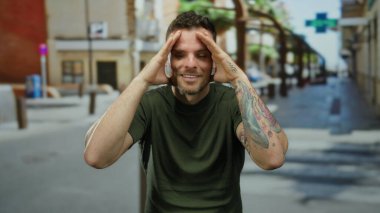 Sokak geçmişinde dövmeleri olan, yeşil gömlek giyen, kendine güven ve cazibe saçan, şehir yaşam tarzını ön plana çıkaran bir adam..